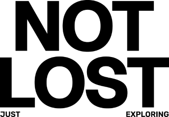 Czarny minimalistyczny napis Not Lost ułożony w dwóch rzędach uzupełniony mniejszymi słowami Just oraz Exploring w dolnych rogach grafiki. Ten typograficzny motyw stanowi hasło przewodnie limitowanej kolekcji ubrań i akcesoriów Kubota x Empik. Nowoczesny design nadruku doskonale wpisuje się w lifestylowy oraz streetwearowy charakter produktów stworzonych w ramach tej wyjątkowej współpracy.